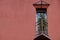 Small triangular balcony in the house with a coral facade and potted flowers on fence. a place to rest your soul