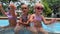 small triplets sisters playing in the pool in swimsuits
