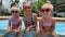 small triplets sisters playing in the pool in swimsuits