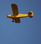 Small two-seat yellow aircraft in flight, tourist plane.