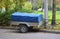 Small two-wheeled gray car trailer is covered with a blue awning