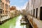 Small venetian canal and old brick walls with vintage traditional balconies. Venice, Italy.