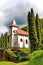 Small village church surrounded by trees with cloudscape on background