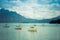 Small vintage sailboats anchoring. Alpine lake and mountains. Retro style.