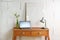 Small vintage table of reddish wood with laptop, desk lamp and a picture frame in front of a raw white wall, tiny home office