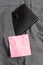 Small wallet in the trousers front pocket beside pink note sheet. Little purse is placed inside man pants near notation