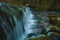 Small water dam at the river spring of Kamniska Bistrica in Slovenia in dry winter time. Cold enchanted waterfall with flowing