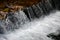 A small waterfall. The height difference of the water flow in the river is equipped with round wooden logs.