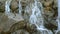 Small waterfall of mountain river rushing cascade over stones.