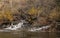 Small waterfall in mountains stream in forest covered mountains of Northern California in late autumn with dead and yellow foliage