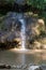 Small waterfall with reflecting lake and sunbeams in forest. Scenie for meditation concept. Biggest waterfall of canton Aargau, in