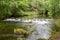 Small waterfall on River Dove running through steep hills in Dovedale