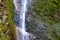 Small waterfall on a rocky stream stone background. Mountain covered with green moss. Concept for refreshing coolness or