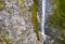 Small waterfall on a rocky stream stone background. Mountain covered with green moss. Concept for refreshing coolness or