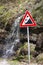 Small waterfall running behind a landslide sign