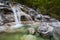 A small waterfall runs over white rock and into an emeral pool