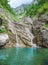 Small waterfall with the water flowing through the rock in a natural pool with turquoise color