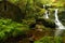 Small waterfalls falling on mossy rocks towards the river.