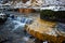 Small waterfalls on the river, limestone layers painted in orange with iron ochre