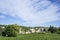 Small wave of beautiful white fluffy clouds on vivid blue sky in a summer time above houses on the mountain, vineyard