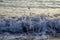 Small wave splash with blurred drops at sandy beach