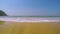 Small waves crush on the shore and move towards the camera.  Blue water with white foam, beach with yellow fine sand on a tropics