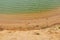 Small waves on greenish water and a sandy beach