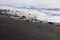 Small waves rolling onto a black sand beach strewn with rocks and pebbles in Hana Bay, Maui, Hawaii