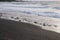 Small waves rolling onto a black sand beach strewn with rocks and pebbles in Hana Bay, Maui, Hawaii