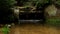 Small weir on river flows out from sandstone cave. Cold water of small river flow over small weir. Stony and rusty construction