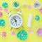 a small white alarm clock, a tampon, pink hearts and multi-colored artificial flowers on a bright yellow background. the concept o