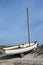 Small white boat on sandy dune by the sea