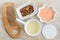 Small white bowls with cosmetic massage, cleansing aroma oil, bath sal foot soak, wooden hair brush, cotton pad, dry herbs