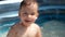 A small white child splashes in the pool in summer.