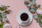 a small white coffee mug on a white saucer. espresso. flatlay. the view from the top. soft pink background with flowers. copyspace