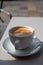 Small white cup of black arabica coffee served outdoor