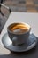 Small white cup of black arabica coffee served outdoor