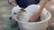 Small white dog bathed with shampoo in warm water in a bowl outside
