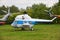 A small white helicopter with a blue stripe on the green grass