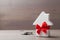 Small white house decorated red bow ribbon with bunch of keys on wooden background. Gift, real estate or buying a new home