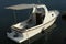 Small white motor fishing boat with wooden helm, simple small cabin in front