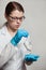 A small white mouse with red eyes in the hand of a scientist in a blue rubber glove.