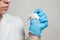 A small white mouse with red eyes in the hand of a scientist in a blue rubber glove.