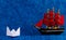 A small white paper boat and a toy ship behind representing professionalism concept