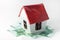 Small white porcelain house with a red roof and money euro banknotes
