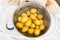 Small white potatoes, washed and scrubbed, in a bowl with water