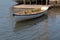 Small white rowboat moored by dock and stone wall