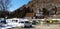 Small white van parked on street and people working and repairing or fixing damaged roads with snow on mountain and blue sky