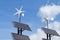 Small wind power generators and set of Solar panels agains blue sky with white clouds.