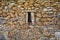 Small window in a beautiful and old stone wall with moss and vegetation